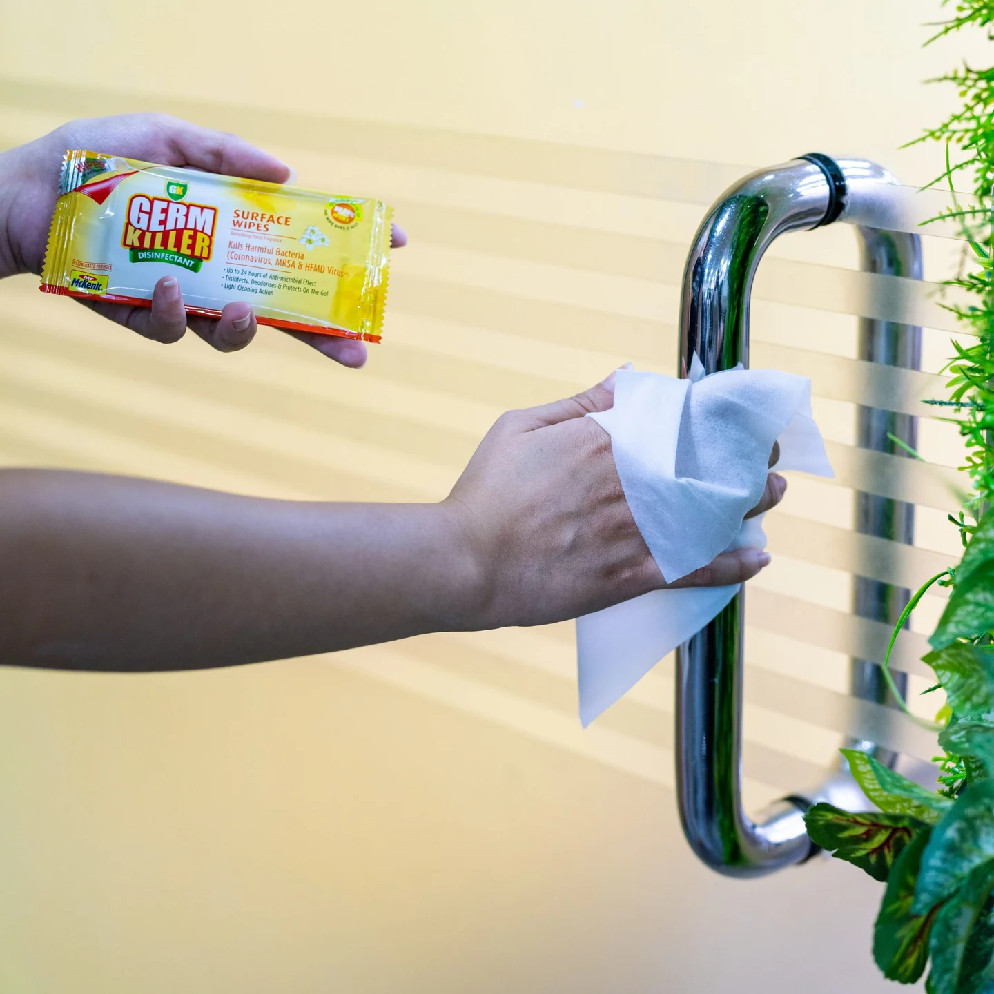 A hand using GK Surface Wipes on an office door handle
